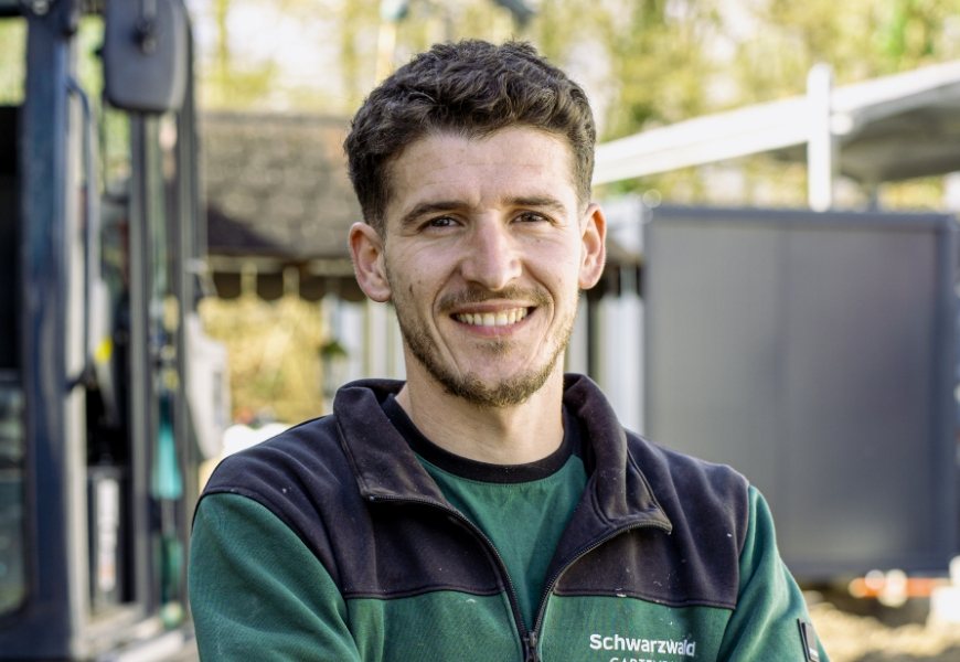 Porträt eines älteren Mitarbeiters in Arbeitsjacke vor einem Fahrzeug