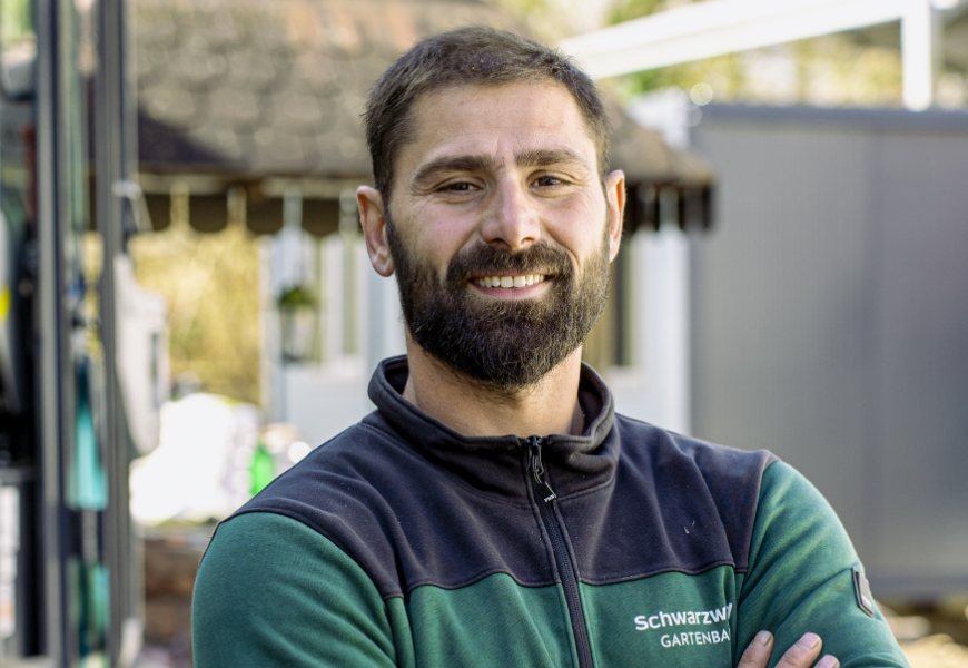 Porträt eines Mitarbeiters im Firmen-Fleece auf dem Betriebsgelände