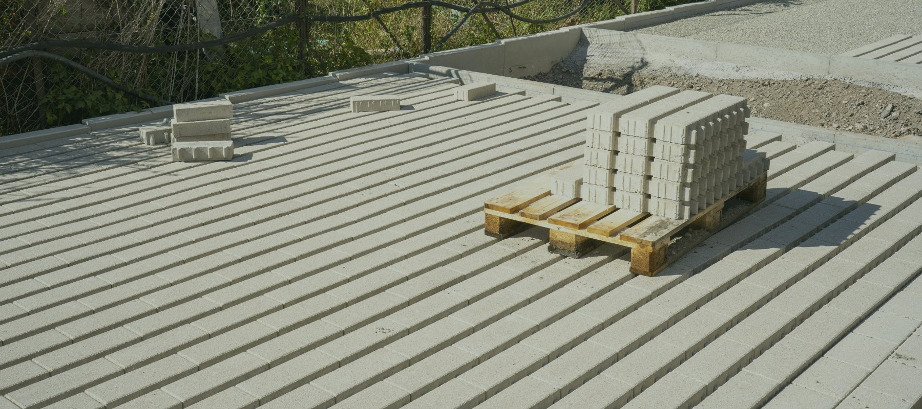 Gestapelte Betonsteine auf einer Palette auf frisch verlegtem Pflaster