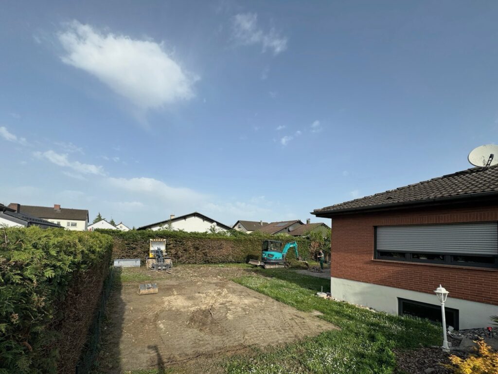 Vorher: Leeres Gartengrundstück mit Bagger im Hintergrund