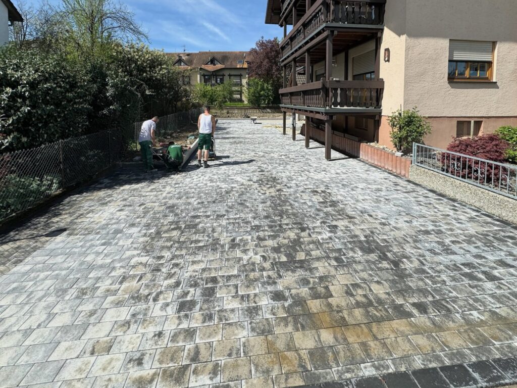 Nachher: Neu gepflasterter Hof vor einem Haus mit Holzbalkonen