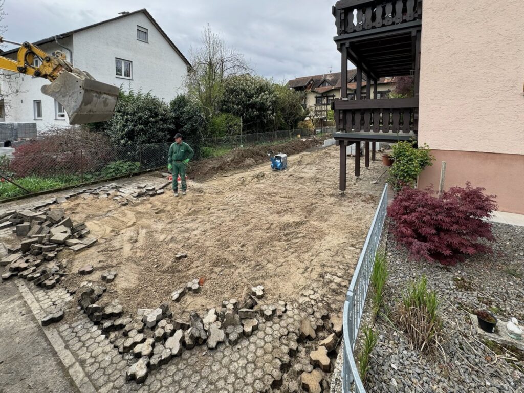 Vorher: Hof mit aufgenommenem Pflaster und Bagger, Mitarbeiter bei den Vorarbeiten