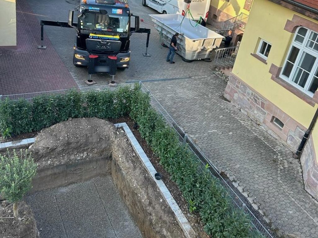 Vorher: Enge Baugrube im Innenhof, davor ein Lieferwagen mit Kran