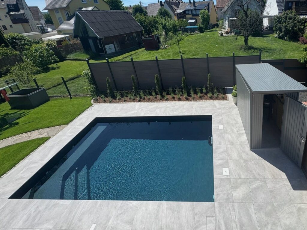 Nachher: Fertiger Pool mit heller Plattenterrasse, Sichtschutz und Gerätehaus