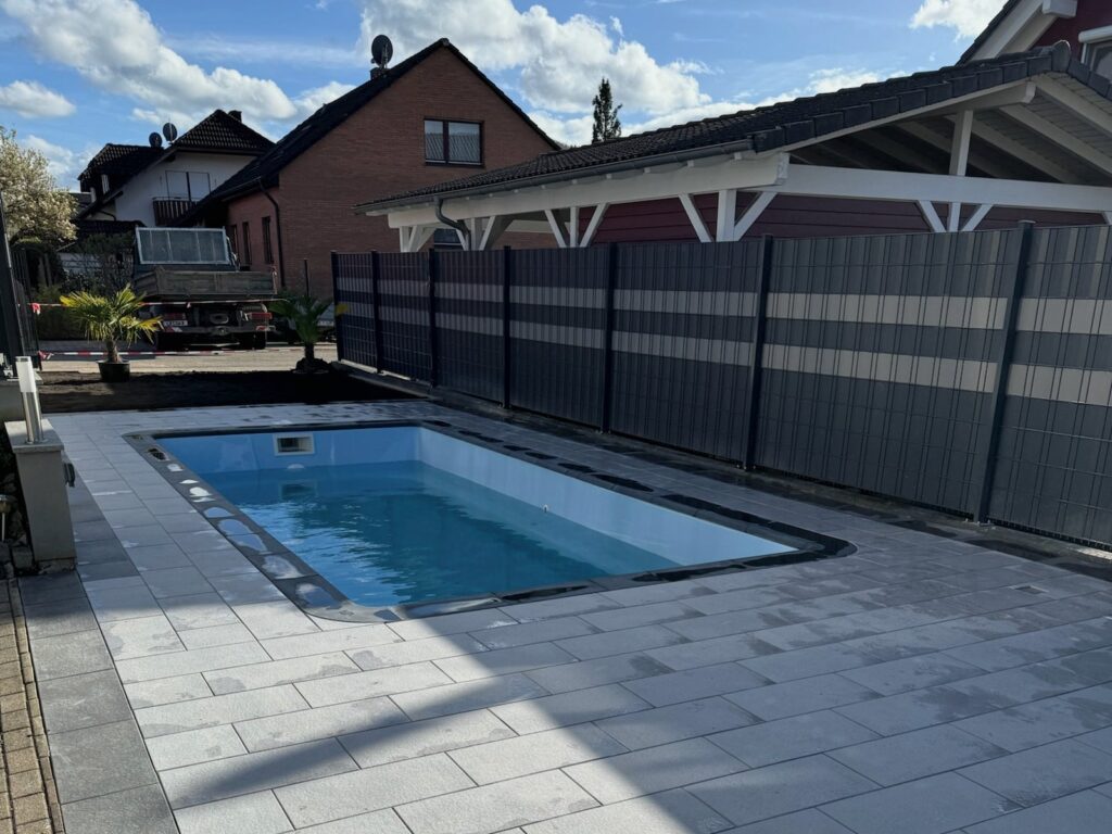 Nachher: Fertiger Pool mit grauem Plattenbelag im schmalen Garten