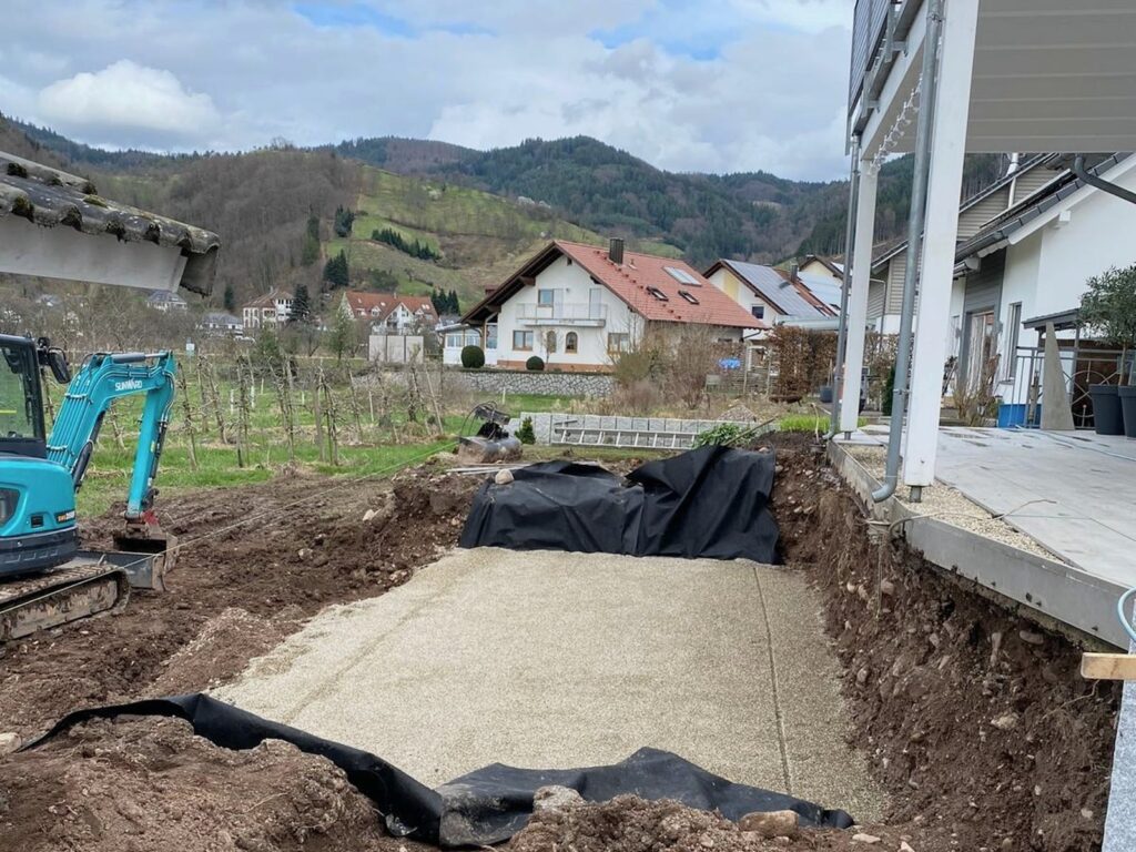 Vorher: Baugrube am Weinberg mit Bodenplatte, Folie und Minibagger